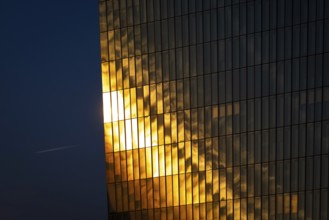 The light of the setting sun is reflected in the glass façade of the European Central Bank (ECB) in
