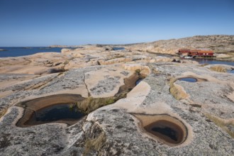 Rocks with rainwater puddles, falun red houses, rocky coast, Bohus granite, Ramsvik, nature reserve