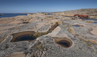 Rocks with rainwater puddles, falun red houses, rocky coast, Bohus granite, Ramsvik, nature reserve