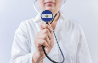 Female doctor holding stethoscope with El Salvador flag. National health system of El Salvador
