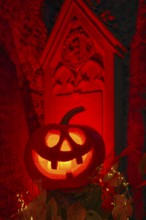 Halloween pumpkin with candlelight in the cemetery, illuminated red and spooky