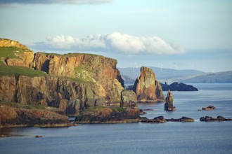Cliffs and rock formations by the sea with wind turbines in the background, Eshaness, Shetland