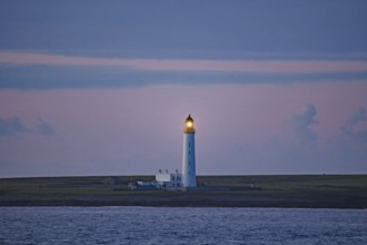 Lighthouse at dusk illuminating the sea, Orkney Islands, Scotland, Great Britain