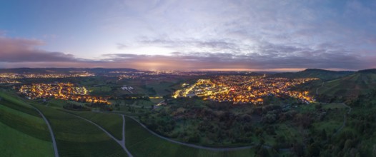 Expansive landscape with illuminated city at dusk and cloudy sky, Korb and Kleinheppach in Rems