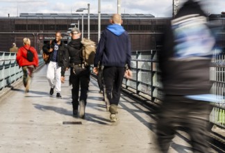 People walking across a bridge at Warschauer Straße station, Berlin, 02 October 2025, Berlin,