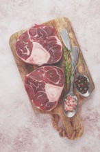 Knuckle on the bone, raw ossobuco meat, on a wooden chopping board, with spices, top view, no