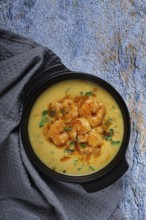 Creamy shrimp curry with spices, garnished with herbs, on a textured background, homemade, no