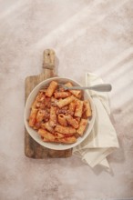 Rigatoni pasta with meat sauce and parmesan cheese on a light table, top view, homemade, no people