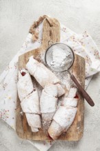 Bagels with filling, sweet pastries, sprinkled with powdered sugar, on a wooden board, dessert,