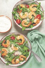 Two bowls of shrimp salad, arugula and cherry tomatoes, with parmesan cheese, healthy food