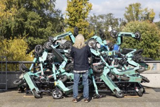 A man looks at an exhibit with stacked e-scooters on the roof terrace of the Haus der Kulturen der