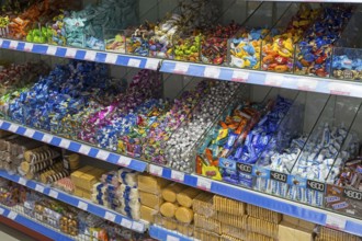 Shelves full of colourful candy wrappers and biscuits in a supermarket, affordable prices and