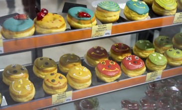 Donuts with colourful glazes and faces in a glass display, Gntunik supermarket, Aragazotn province,