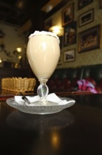 A coffee drink with whipped cream sits on a table in an English pub