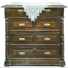 A vintage chest of drawers covered with an openwork crocheted doily