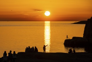 Silhouettes of tourists, sun melting in the sea, sunset, archipelago landscape, Smögen,
