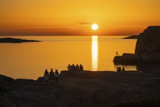 Silhouettes of tourists, sun melting in the sea, sunset, archipelago landscape, Smögen,