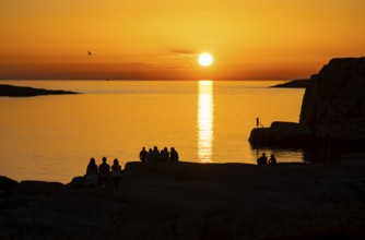 Silhouettes of tourists, sun melting in the sea, sunset, archipelago landscape, Smögen,