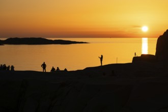 Silhouettes of tourists, sun melting in the sea, sunset, archipelago landscape, Smögen,