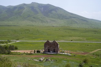 Small stone church in a vast green landscape in front of a mountain with clouds, Saint Trinity