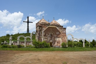 Stone architecture church with arches and cross on a hill under a cloudy blue sky, Monument of the
