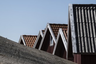 Gable of boat shed behind a rock, girl jumping from a high wooden diving platform, lido,