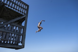 Girl jumping from a high wooden diving platform into the sea, lido, Fjällbacka, Bohuslän, West