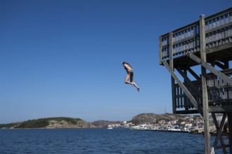 Girl jumping from a high wooden diving platform into the sea, lido, Fjällbacka, Bohuslän, West