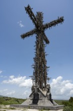 High metal cross with complex structure under a blue sky with clouds, Monument of the Holy Cross,