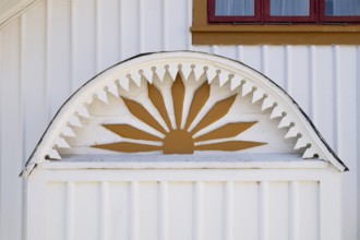 Detail of an ornament symbolising the sun in yellow and white on a wooden house, Fjällbacka,