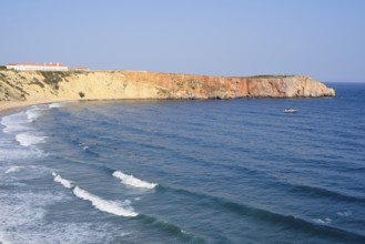 Cliffs with the Hotel Pousada de Sagres and surfers in the sea, Praia da Mareta, Sagres, Algarve,