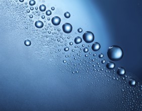 Macro shot of clear water droplets spread on a smooth blue surface, creating a refreshing and