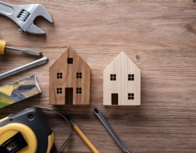 A detailed layout of miniature wooden houses accompanied by various tools on a textured wooden
