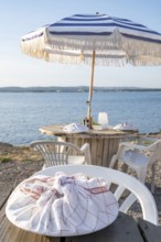 A plate wrapped in a red and white chequered tea towel lies on a rustic wooden table in the