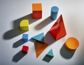 Vividly colored geometric shapes, including spheres and pyramids, artfully arranged on a surface.
