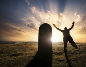 A silhouette of a lone figure walking off a gravestone, The scene evokes Resurrection thoughts