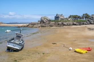 On the harbour beach of Tregastel on the Cote de Granit Rose, small boats lie on the light sand at
