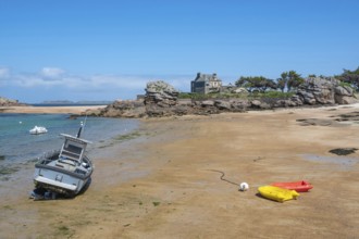 On the harbour beach of Tregastel on the Cote de Granit Rose, small boats lie on the light sand at