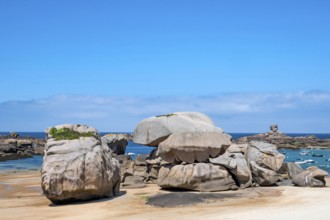 Spectacular pink granite rocks, sculpted by wind and sea, pile up on the beach of the Cote de