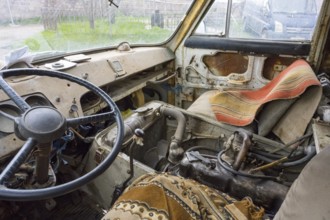 The interior view of an old lorry shows the steering wheel and worn seats, roadworthy, van,
