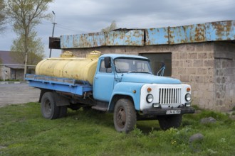 An old blue lorry with yellow tanks stands abandoned in a rural setting, GAZ-53 lorry, tanker,
