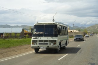 A bus travelling on a road along a rural and mountainous landscape with a cloudy sky, PAZ-3205 Bus,
