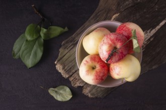 Apples lie in a round white plate on a wooden background
