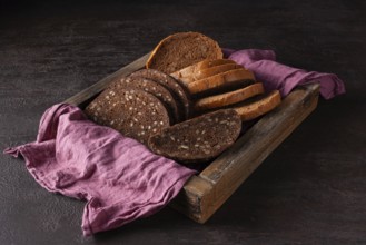 Healthy bread with sprouted grains lies in a wooden box on a pink cloth