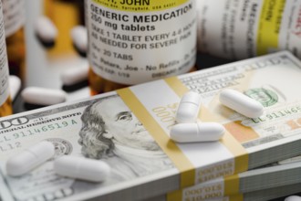 Prescription medicine bottles and pills next to stacks of 100 dollar bills