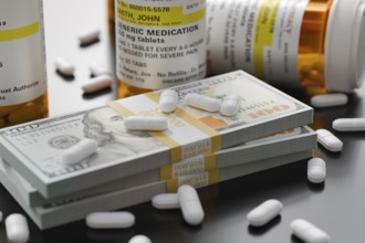 Prescription medicine bottles and pills next to stacks of 100 dollar bills