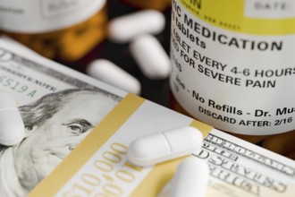 Prescription medicine bottles and pills next to stacks of 100 dollar bills