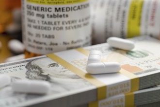 Prescription medicine bottles and pills next to stacks of 100 dollar bills