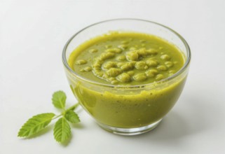 A vibrant image showcasing a bowl of homemade pesto sauce, accompanied by fresh green leaves, set