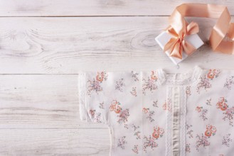 Shirt for newborn toddler and gift box on white wood